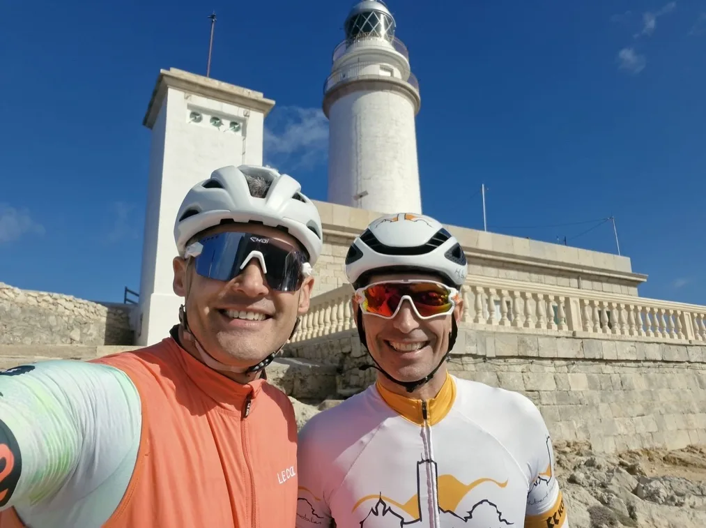 Sebastian Gratz und Hubert Hammerl mit Radhelmen vor einem Leuchtturm auf Mallorca